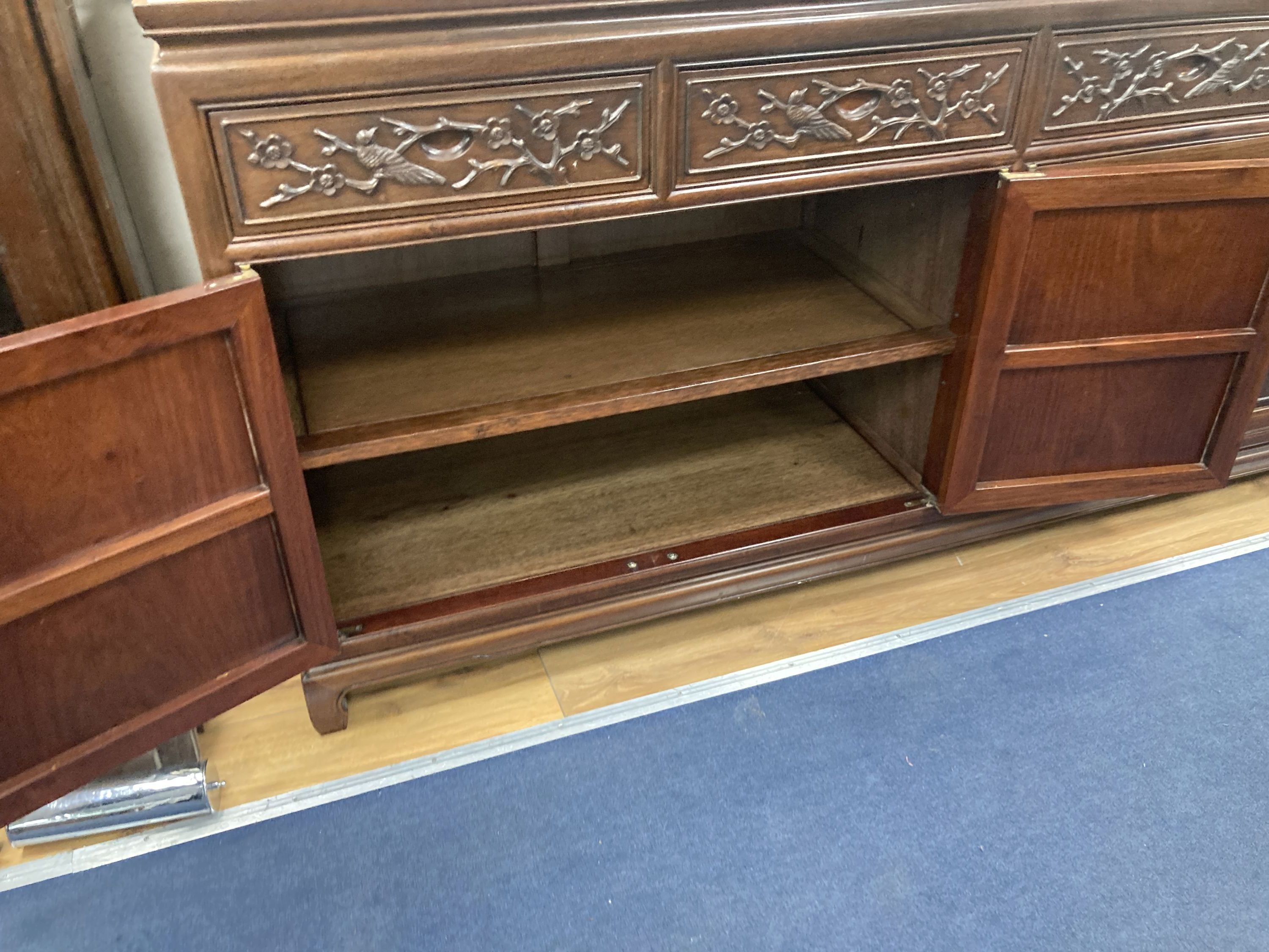A 20th century Chinese carved hardwood dining room suite comprising sideboard fitted with four drawers above four carved panelled cupbo